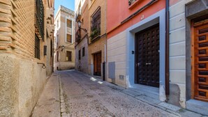A narrow cobblestone street flanked by buildings with traditional architecture, including a wooden door and a barred window. - Toledo Ap (Toledo)
