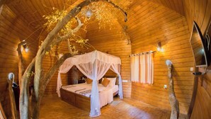 A cozy wooden cabin bedroom with a canopy bed, wooden walls, and a rustic ambiance. - La Pentera (Thanamalvila)