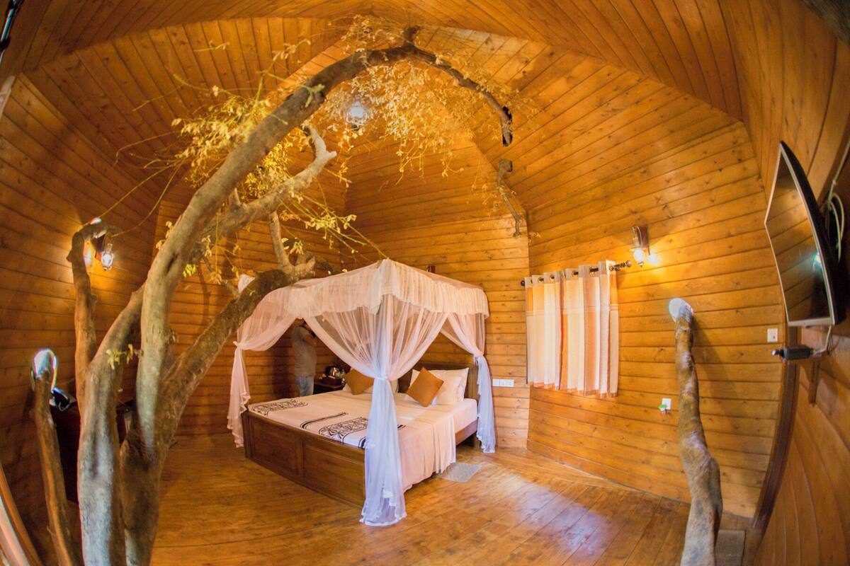 A cozy wooden cabin bedroom with a canopy bed, wooden walls, and a rustic ambiance.