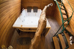 Uma cabana de madeira com uma banheira grande, uma escada e um cão dentro da banheira.