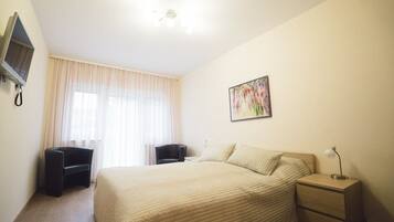 Una camera d'albergo con un letto, una scrivania, una sedia, un televisore e un quadro appeso al muro.