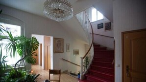 Een ruime kamer met een rode trap, een kroonluchter en een grote plant.
