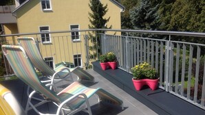 Een balkon met gestreepte lounge fauteuils en potplanten.