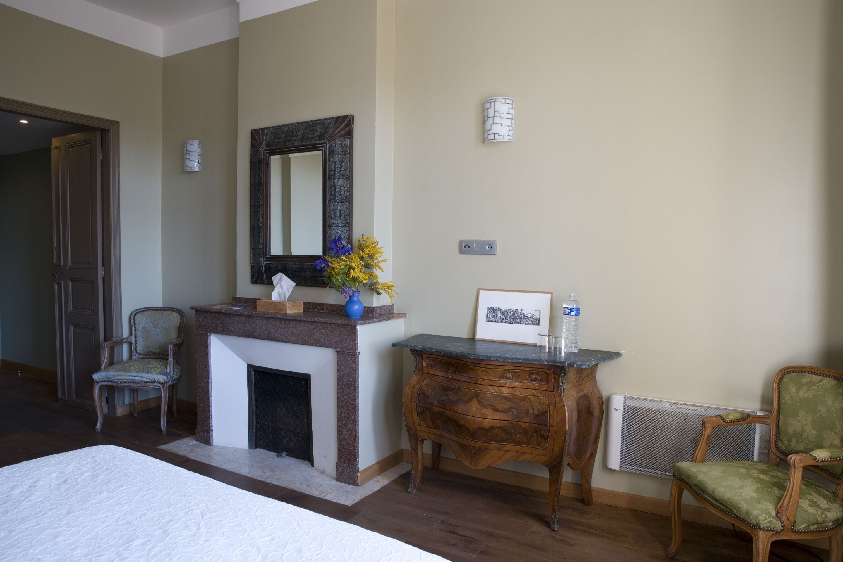 Habitación de hotel con cama, chimenea, espejo, escritorio y dos sillas.