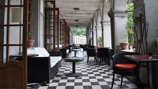 An indoor patio area with checkered flooring, black and white furniture, and potted plants.