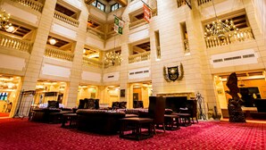 A grand hotel lobby with multiple seating areas, a chandelier, and a coat of arms on the wall. - Nanki Shirahama Resort Hotel (Kamitonda)