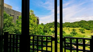 A view through a window with a grid pattern, overlooking a lush green landscape with trees and a distant building. - Nanki Shirahama Resort Hotel (Kamitonda)