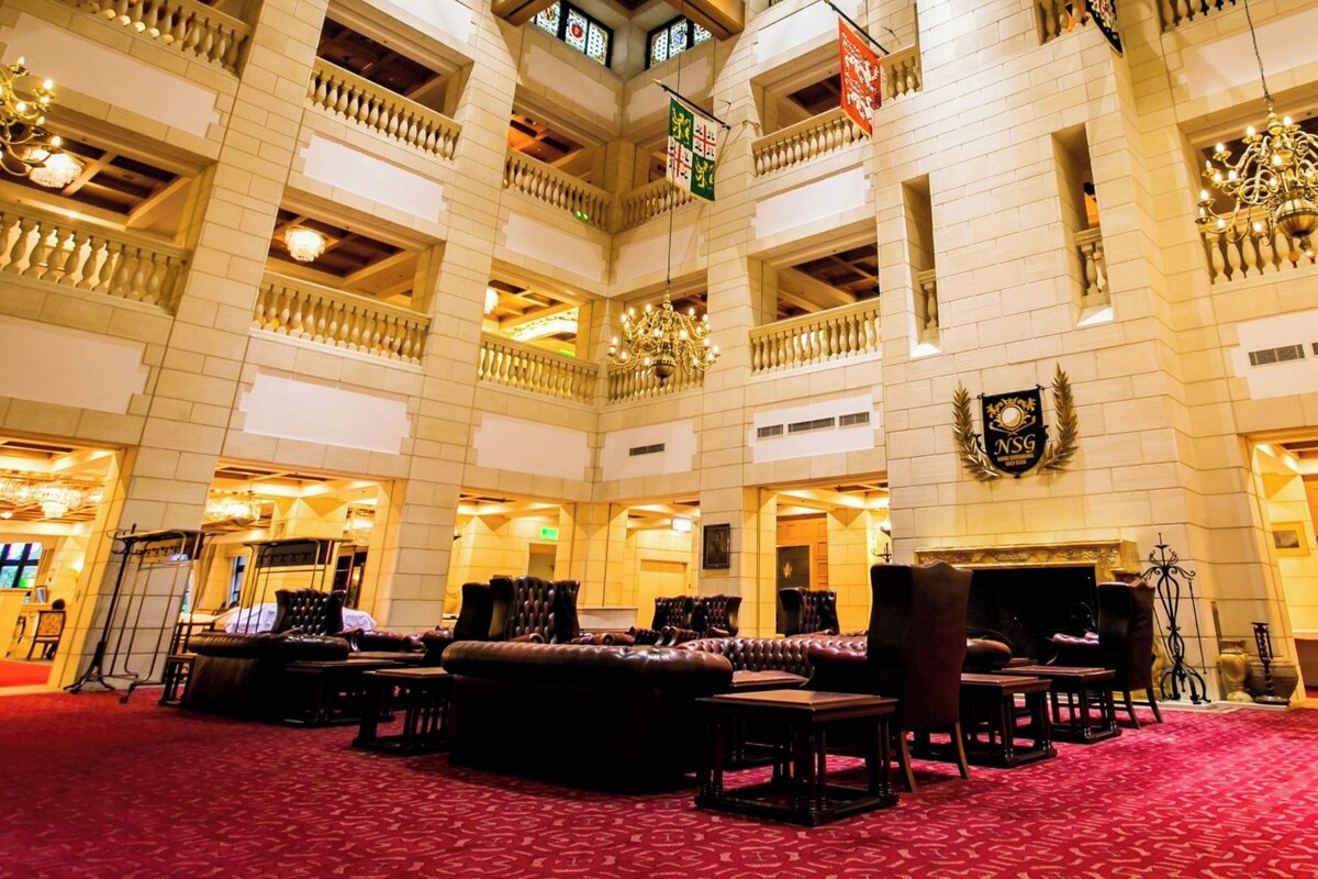 Un vaste hall d’hôtel comprenant plusieurs espaces de détente, un lustre et un vestiaire.