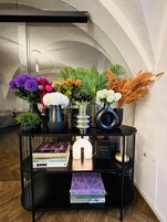 Una consola negra decorada con diversos objetos, como libros, una lámpara pequeña y arreglos florales.