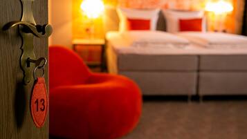 Een hotelkamer met een bed, een rode relaxstoel en een sleutelhanger met het getal 13.