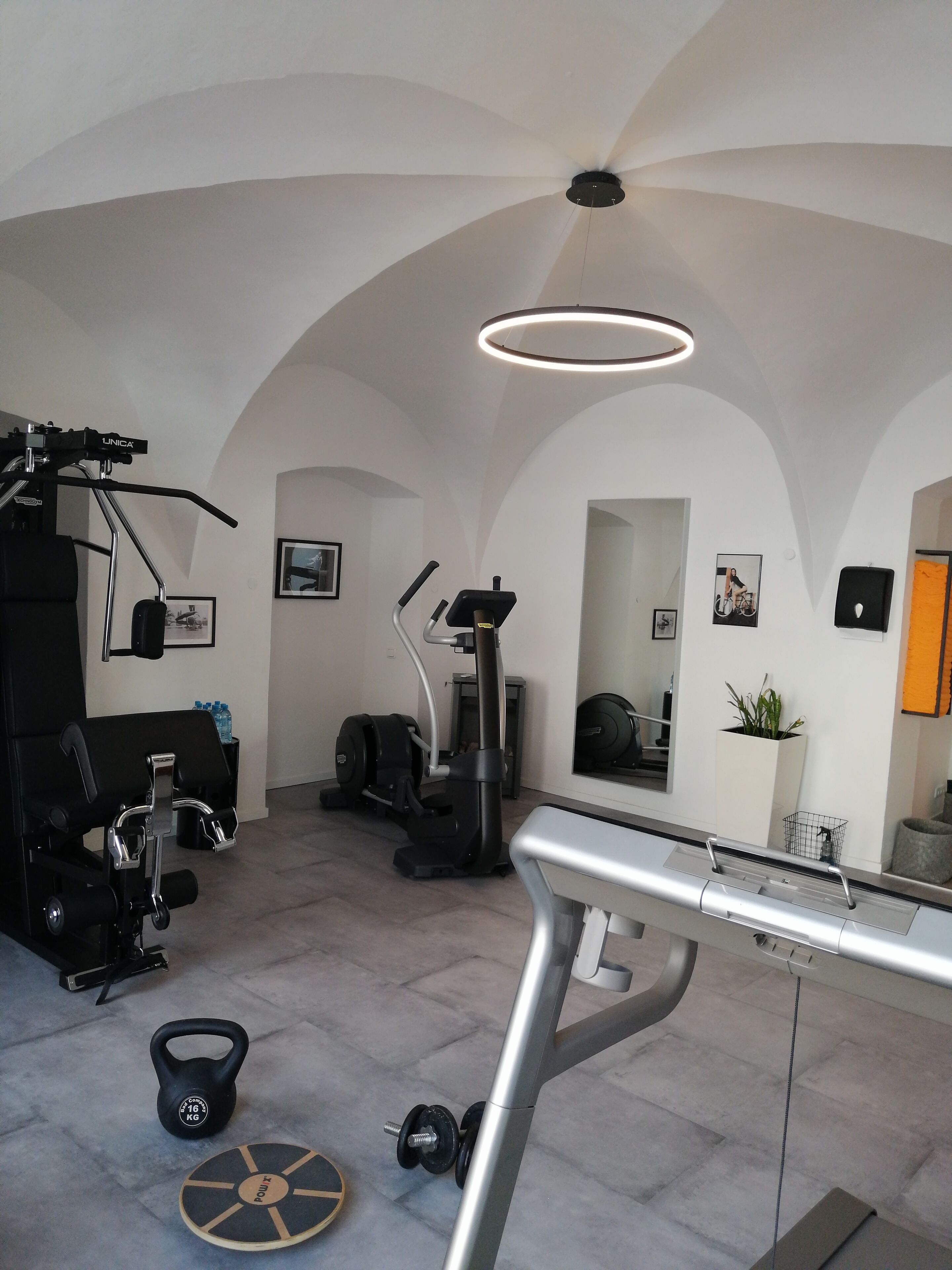 A gym with a ceiling fan, exercise equipment, a kettlebell, and a weight plate.