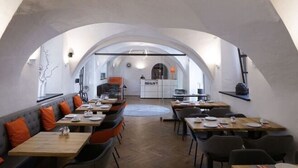 A restaurant with a high arched ceiling, wooden flooring, and a mix of seating including tables and a sofa. - Hotel Maxplatz (Hof)