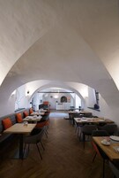 Un restaurante con techo abovedado, suelo de madera y una variedad de asientos, incluyendo mesas y un sofá.