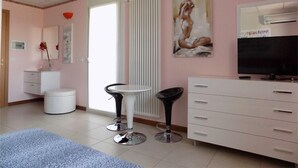 A bedroom with a bed, two chairs, a dresser, a TV, and a radiator. - Hotel Residence Sole (Fontanafredda)