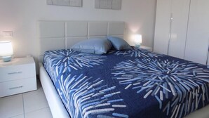 A bedroom with a bed, two nightstands, a white headboard, and two wall-mounted flower paintings. - Hotel Residence Sole (Fontanafredda)