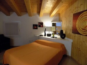 Une chambre à coucher avec un lit, une table de chevet, une lampe, un miroir et un tableau accroché au mur.