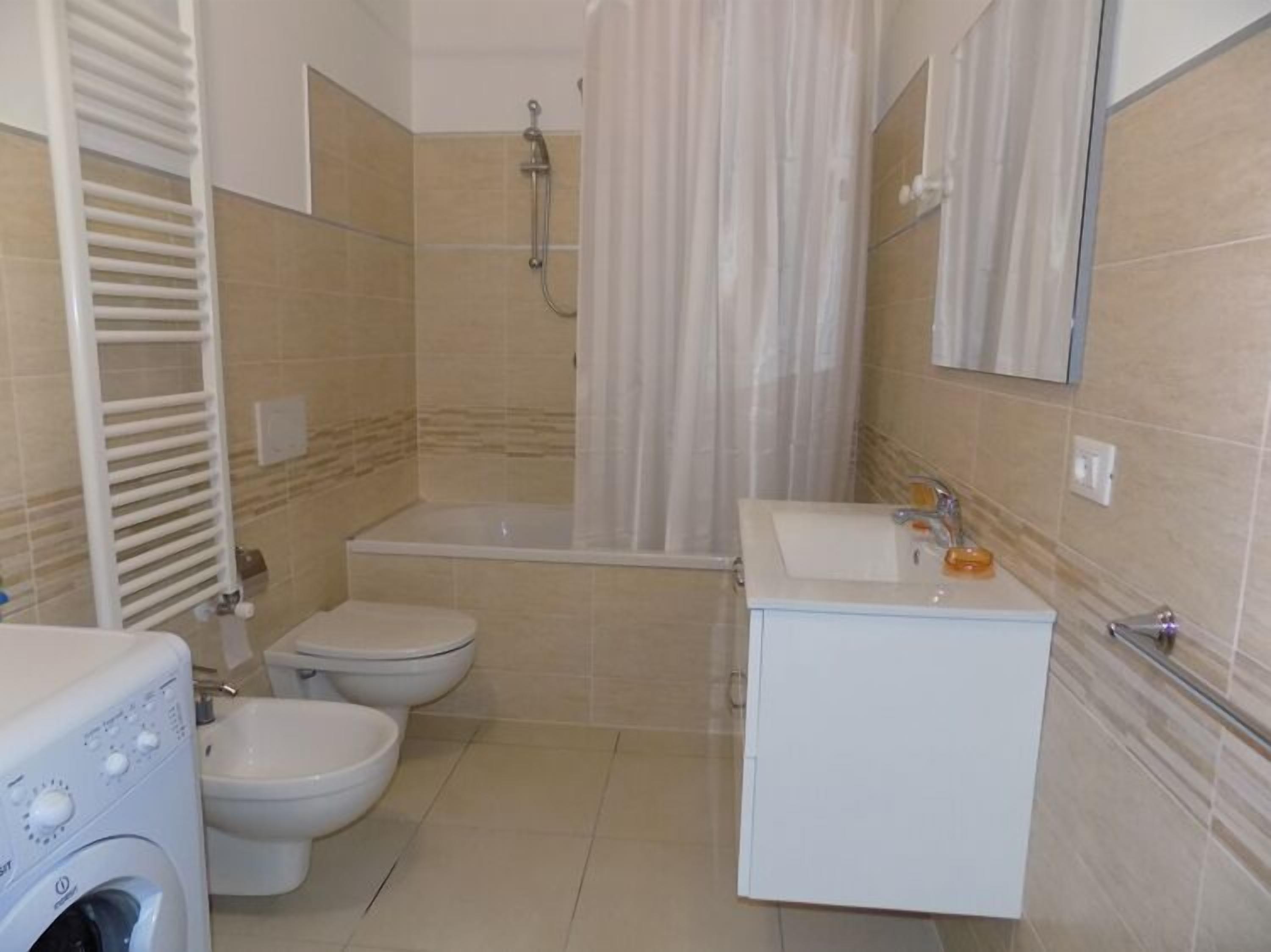 Un baño con bañera, inodoro y lavadora.