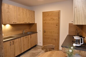 A compact kitchen with wooden cabinets, a sink, and a coffee maker. - Chaletdorf Fanningberg (Weisspriach)