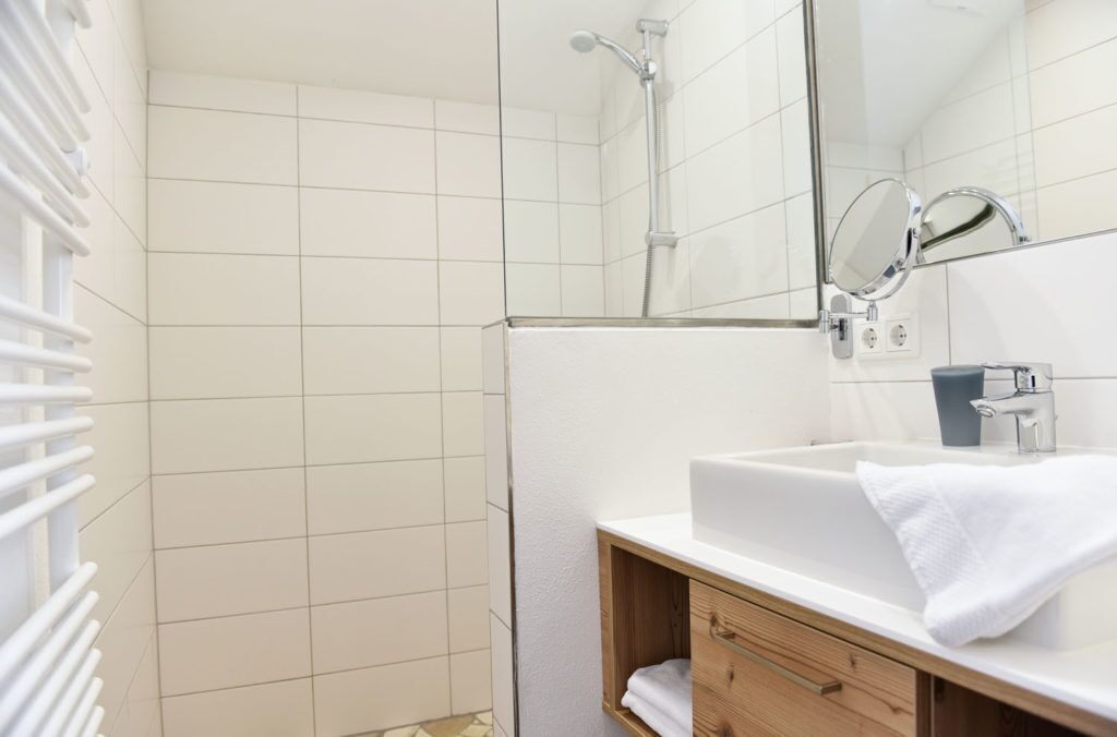 A modern bathroom with a shower, a sink with a mirror, and a towel rack.