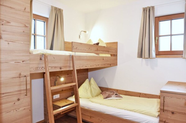 A bunk bed room with a ladder, a bedside table, and a window with curtains. - Chaletdorf Fanningberg (Weisspriach)