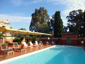A swimming pool with lounge chairs and a covered area. - Hôtel Cyrnea (Calvi)