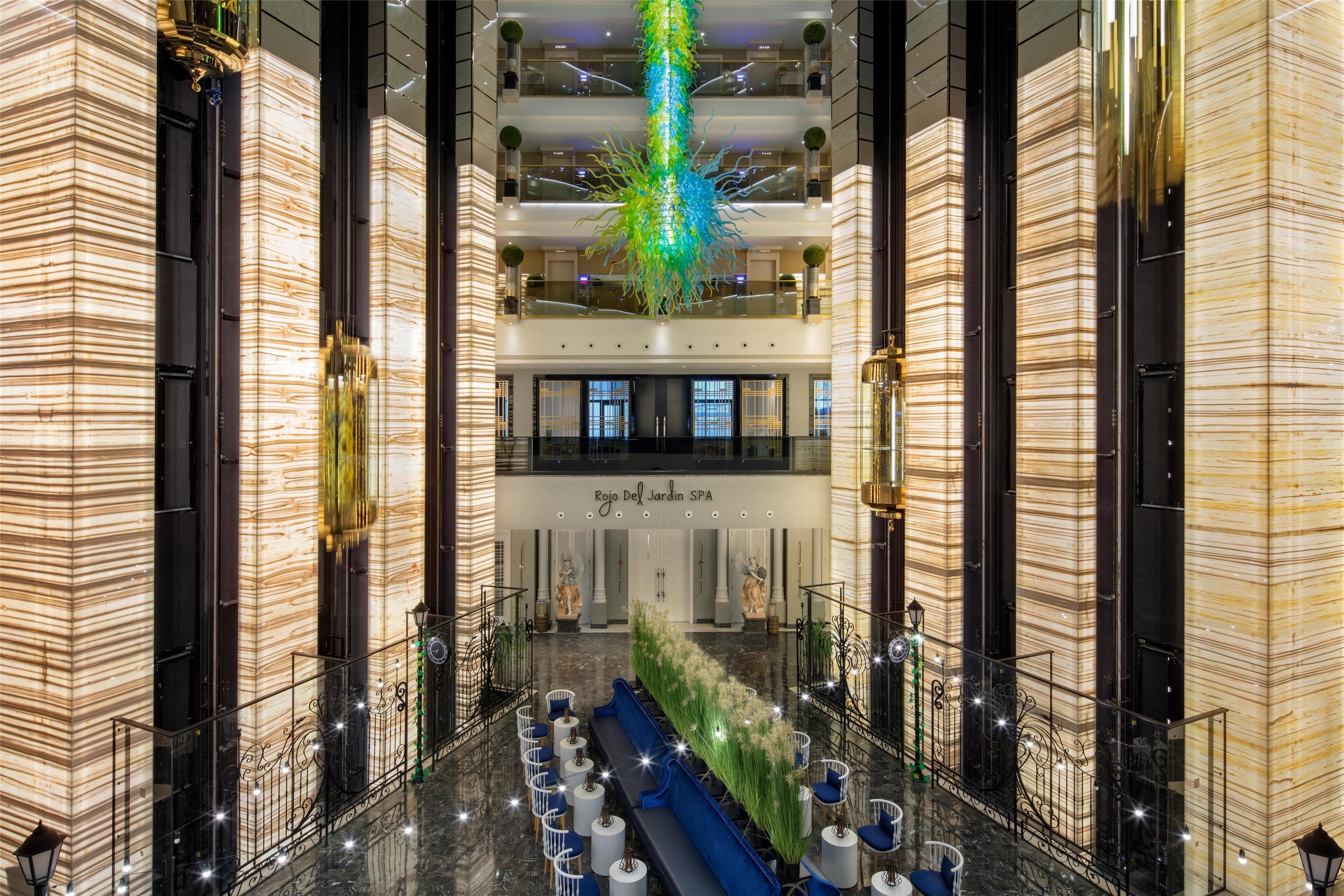 A spacious lobby with a central seating area, a high ceiling, and a modern chandelier.