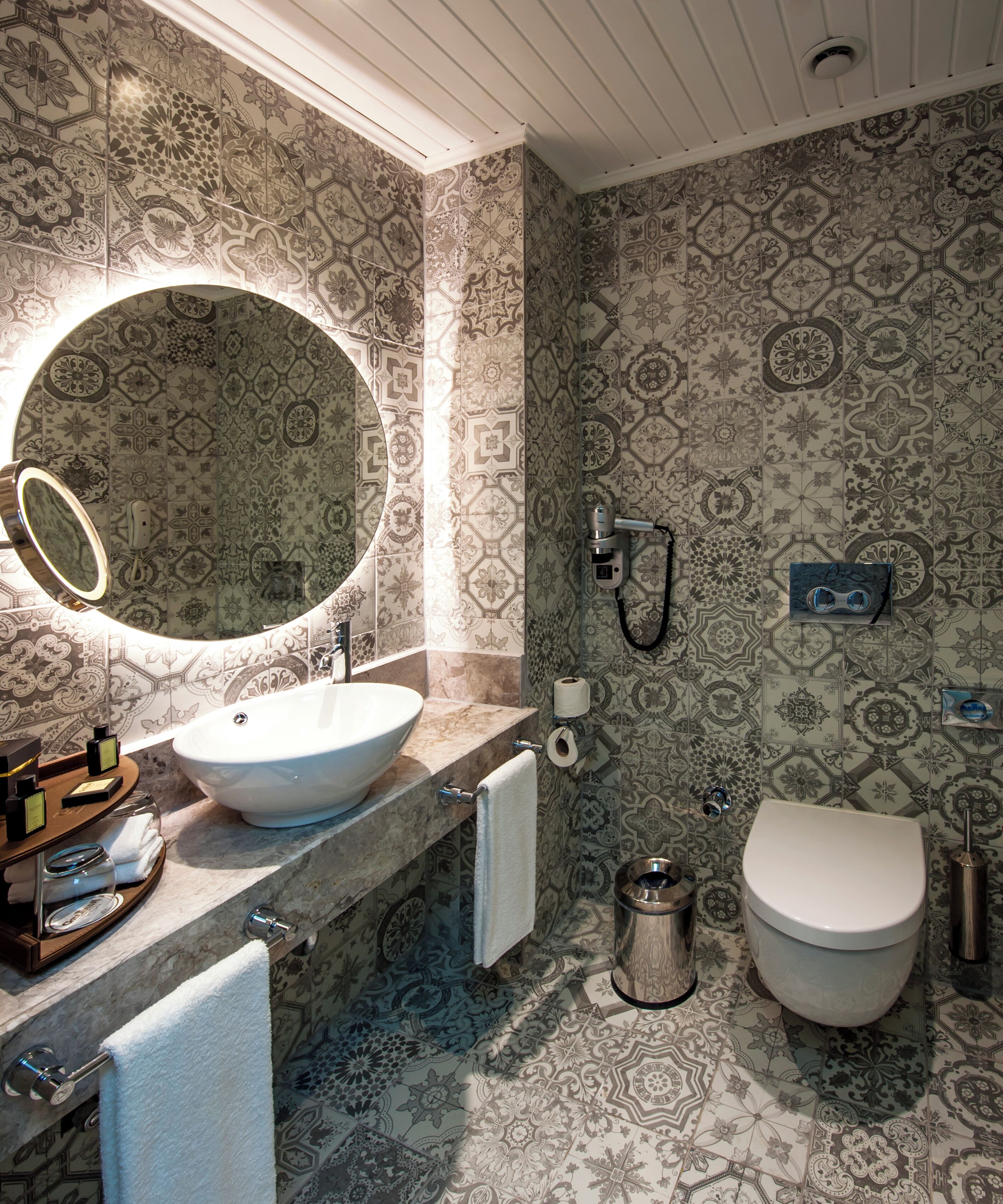 Un baño con un espejo redondo, un lavabo, inodoro y ducha.