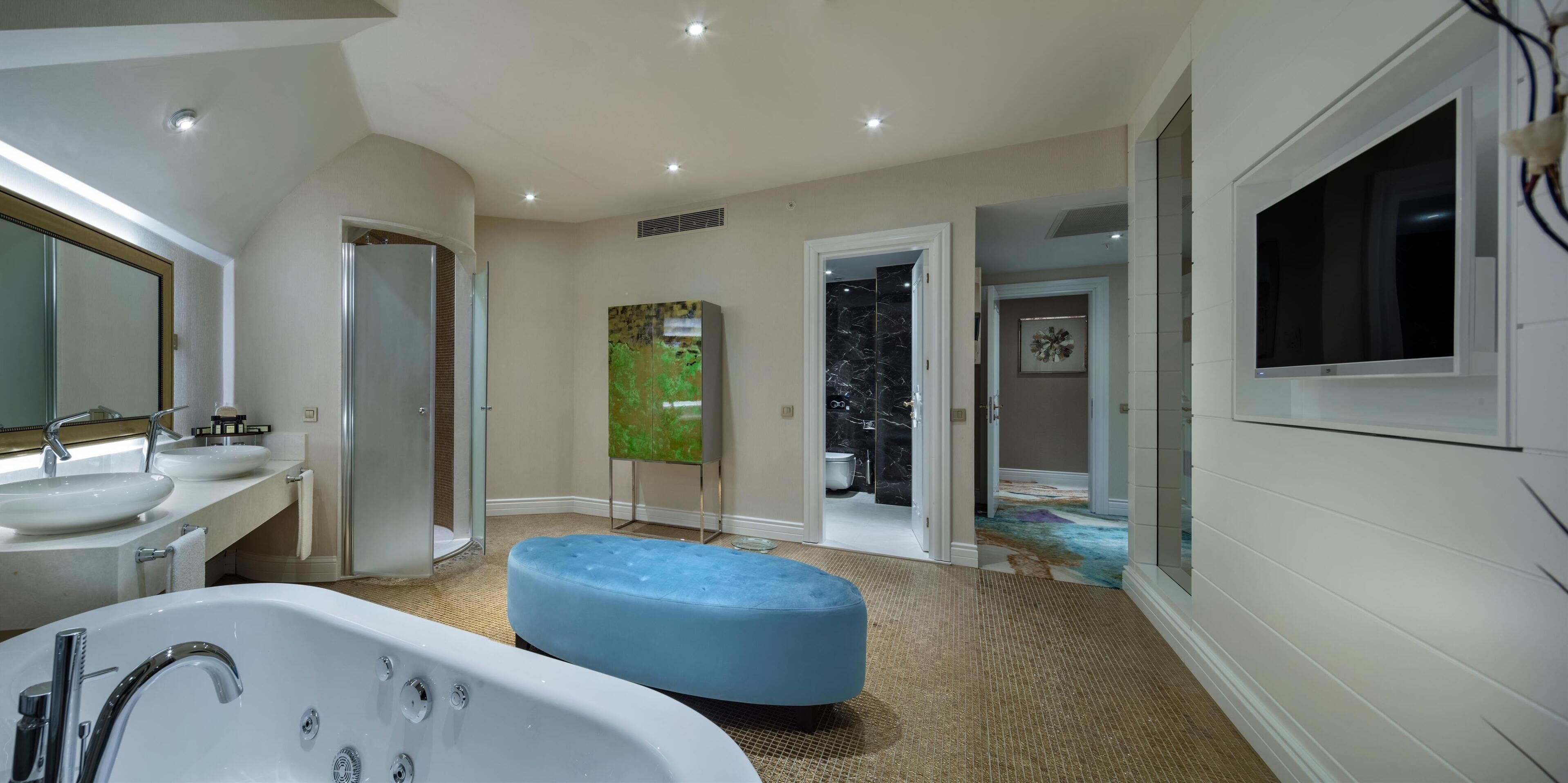 Un bagno moderno con due lavabi, una vasca da bagno spaziosa e un pouf blu.