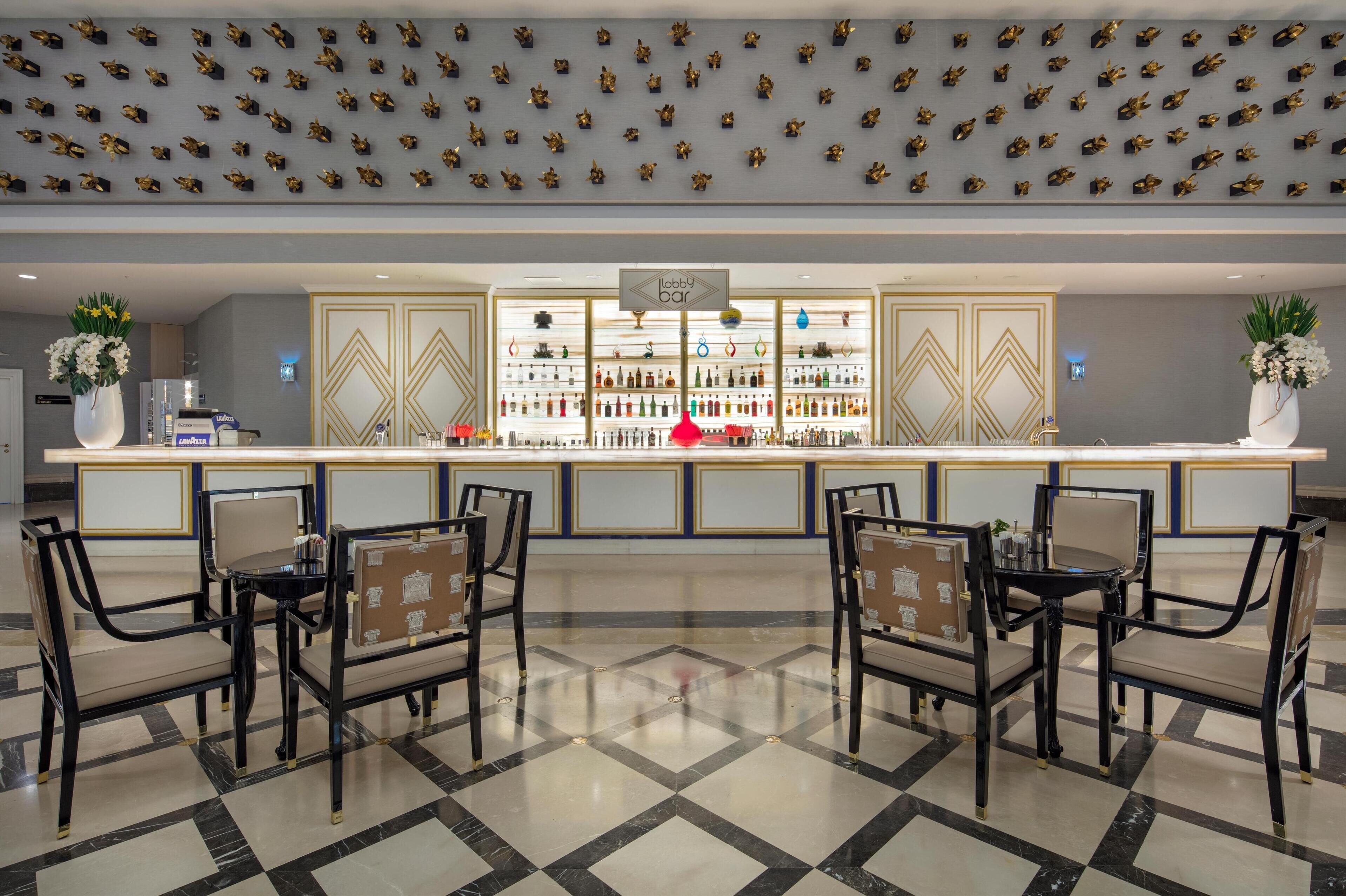 A lobby with a bar area, seating, and a decorative ceiling.