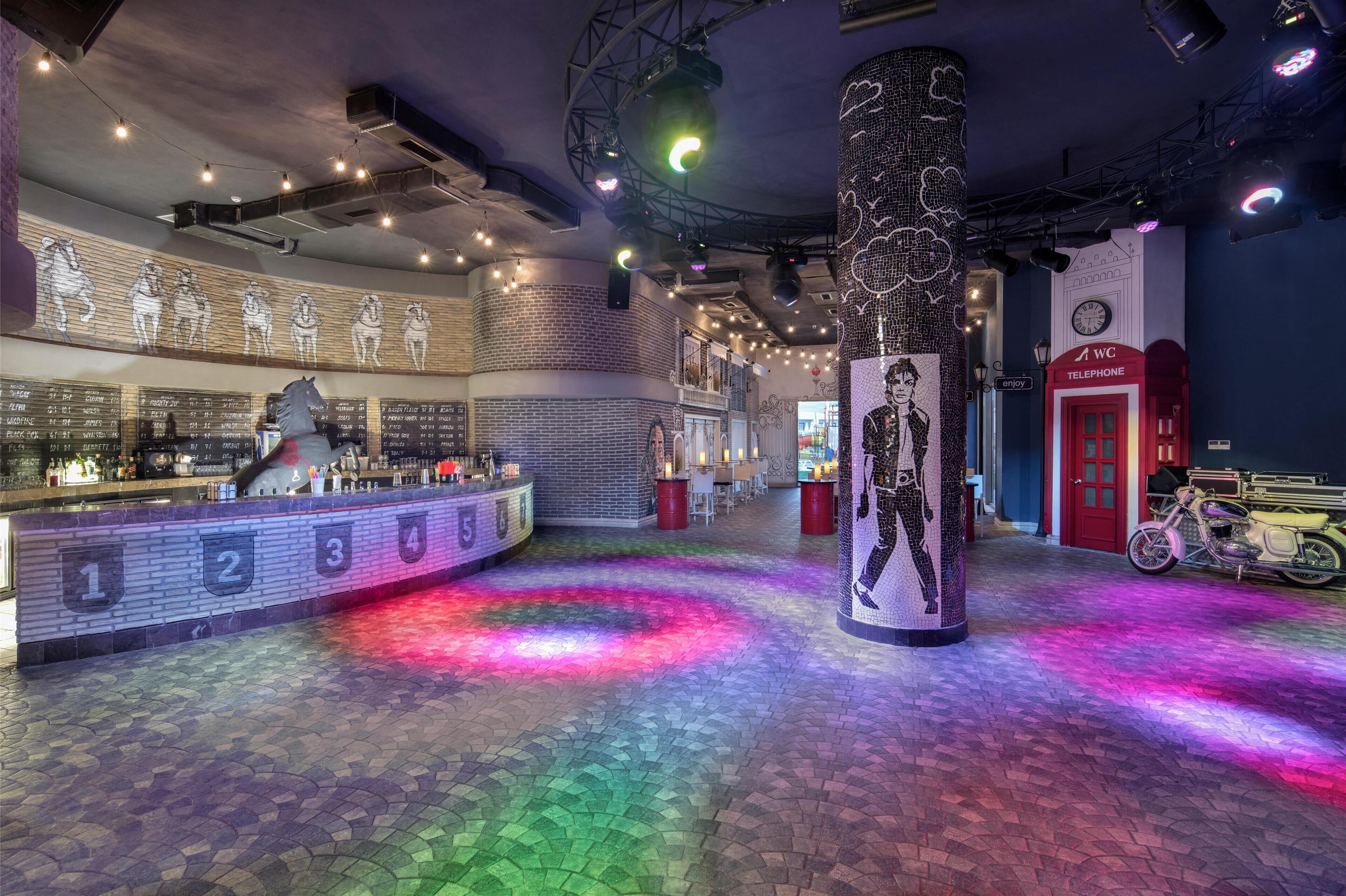 A bar area with a counter, numbered seating, and a large pillar with a mural.