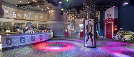 A bar area with a counter, numbered seating, and a large pillar with a mural.