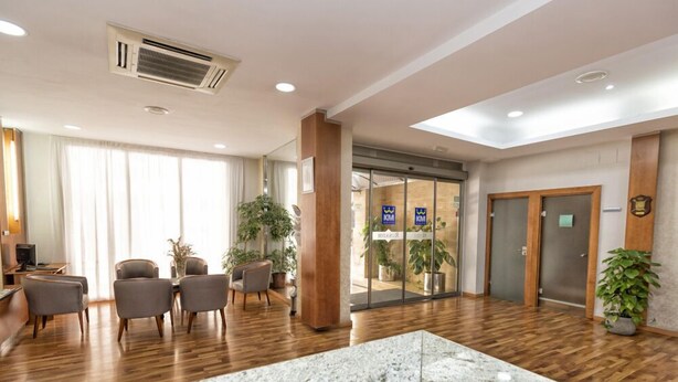 A hotel lobby with a reception desk, seating area, and a large marble counter. - Hotel Rusadir (Melilla)