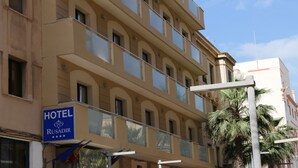 A hotel building with multiple balconies, a sign indicating it is the Rusadir Hotel, and a palm tree in the foreground. - Hotel Rusadir (Melilla)