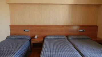 A hotel room with two single beds, a wooden headboard, a bedside table with a phone, and a wall-mounted air vent.