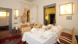 Zona pranzo con tavoli apparecchiati per un pasto, con tovaglie bianche e posate disposte con cura.