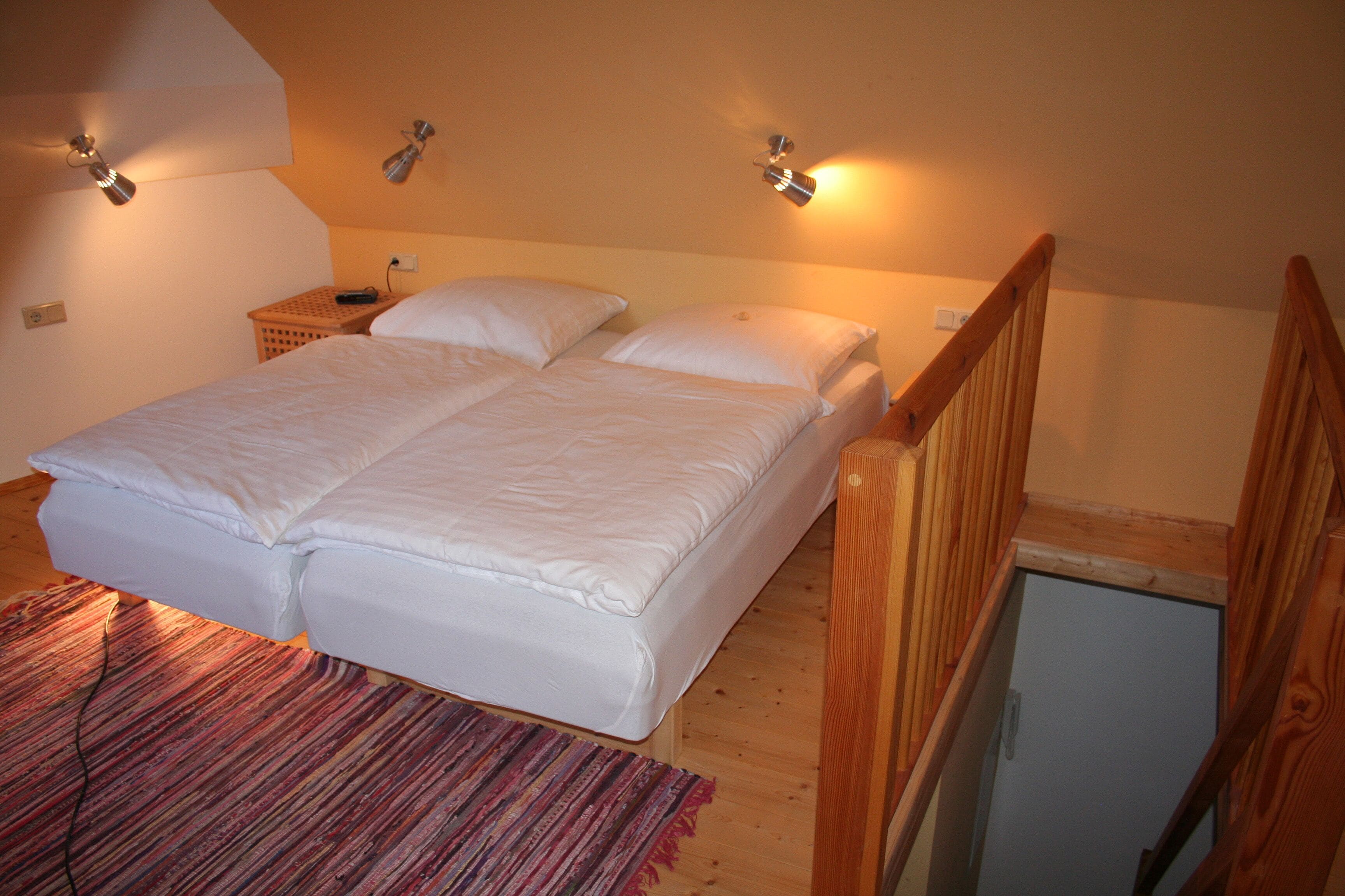 Une chambre avec un lit double, un plancher en bois et une petite table de chevet.