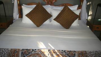 A bed with a canopy, two pillows, and a patterned bedspread.