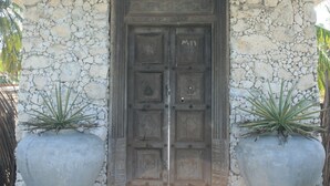 A stone building with a tiled roof, a wooden door, and two large planters. - Villa Setha Wadi (Kalpitiya)