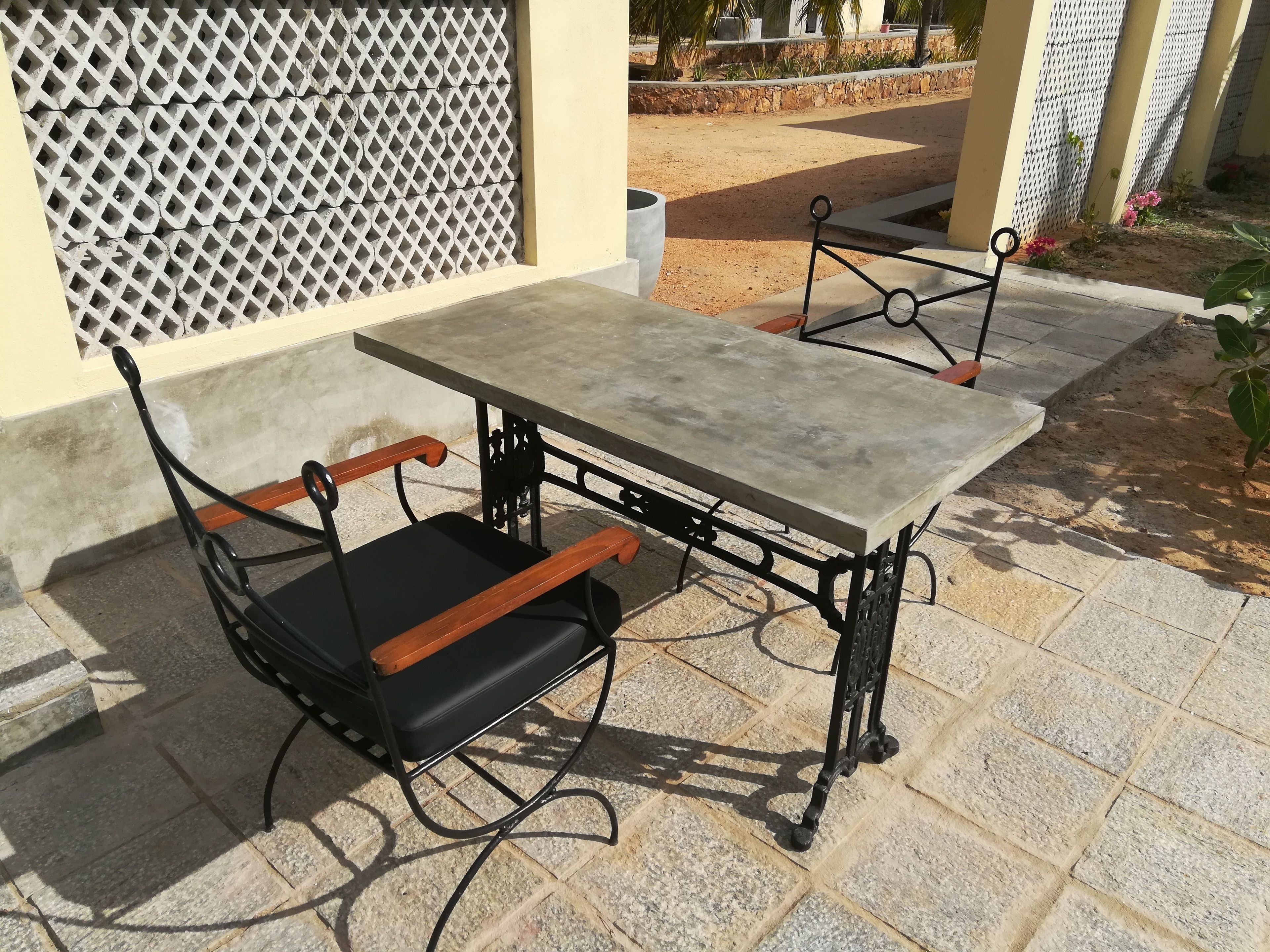 Une table avec un banc, installée sur une terrasse dallée de pierres.
