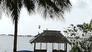 A beach with a wooden pier leading to a thatched-roof hut. A blue canopy and a boat are docked near the hut. - Villa Setha Wadi (Kalpitiya)