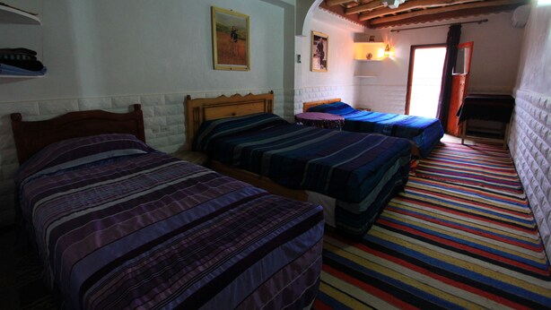 A room with three beds, a colorful striped carpet, and a wooden ceiling. - Maison d'Hôtes La Vallée des Figues (Ait Sedrate Jbel El Soufla)