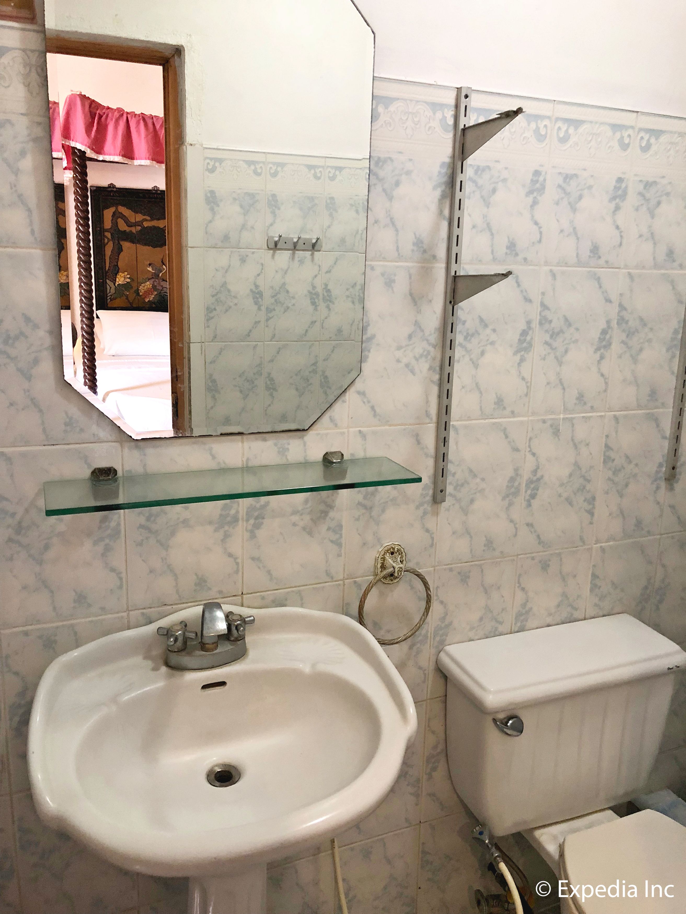 Une salle de bain avec un lavabo blanc, des toilettes, une étagère en verre et un miroir.