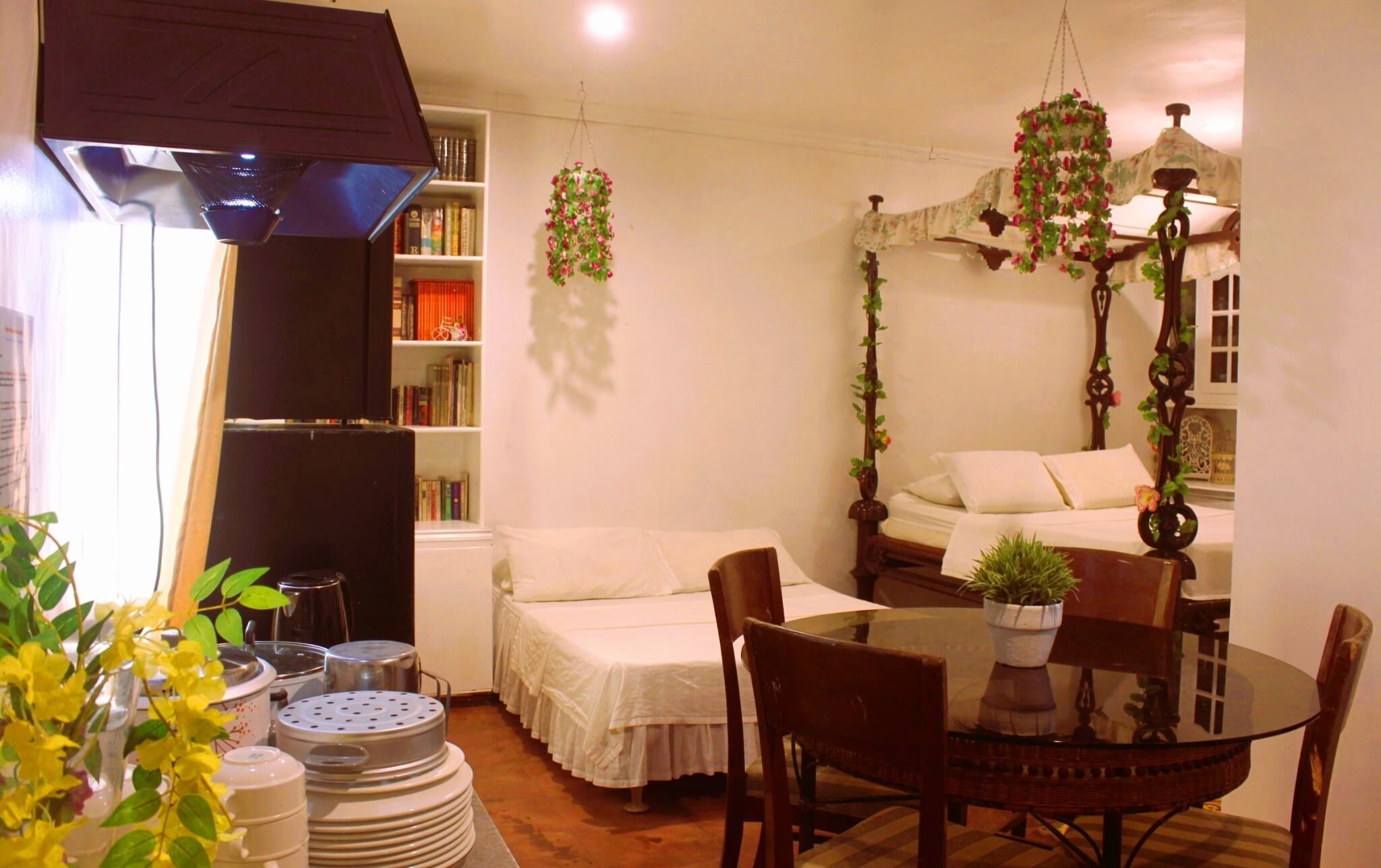 A cozy room with a bed, a dining table, and a bookshelf.