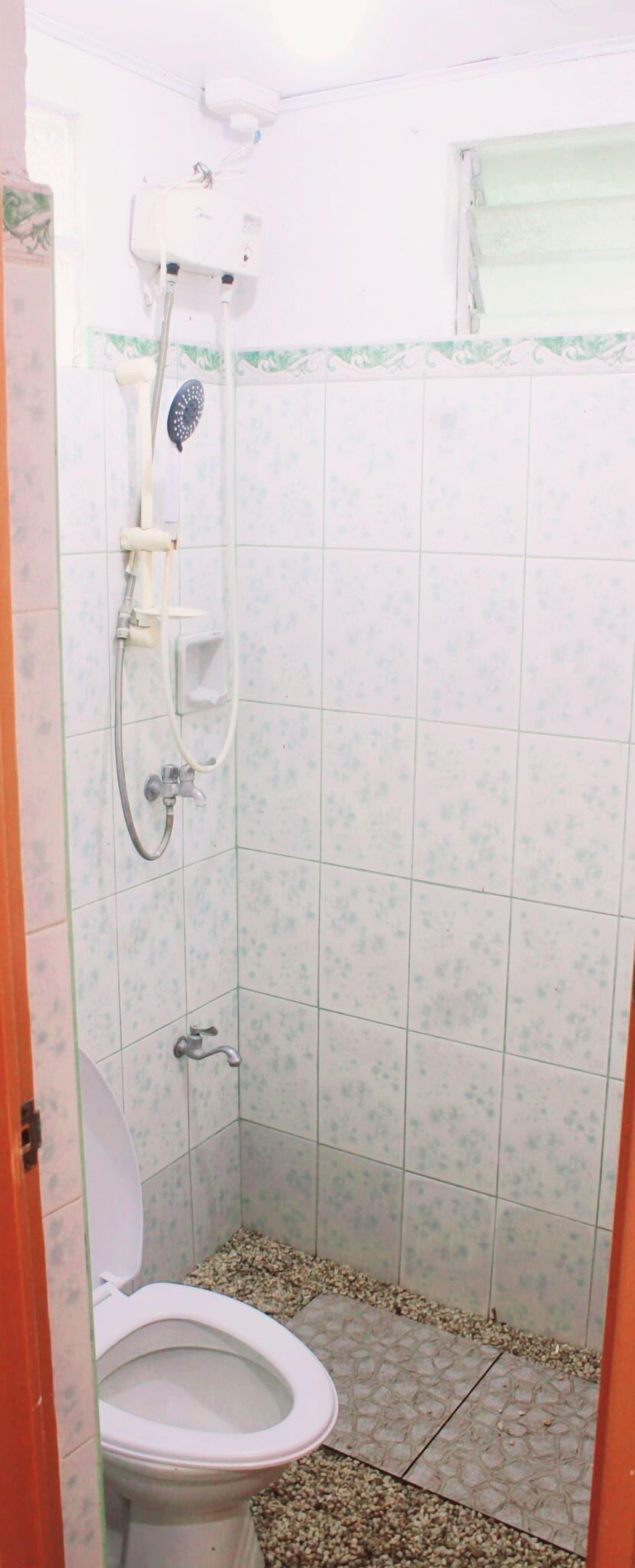 A small bathroom with a toilet, a shower, and tiled walls.