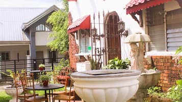 A courtyard with a white urn, chairs, and a table.