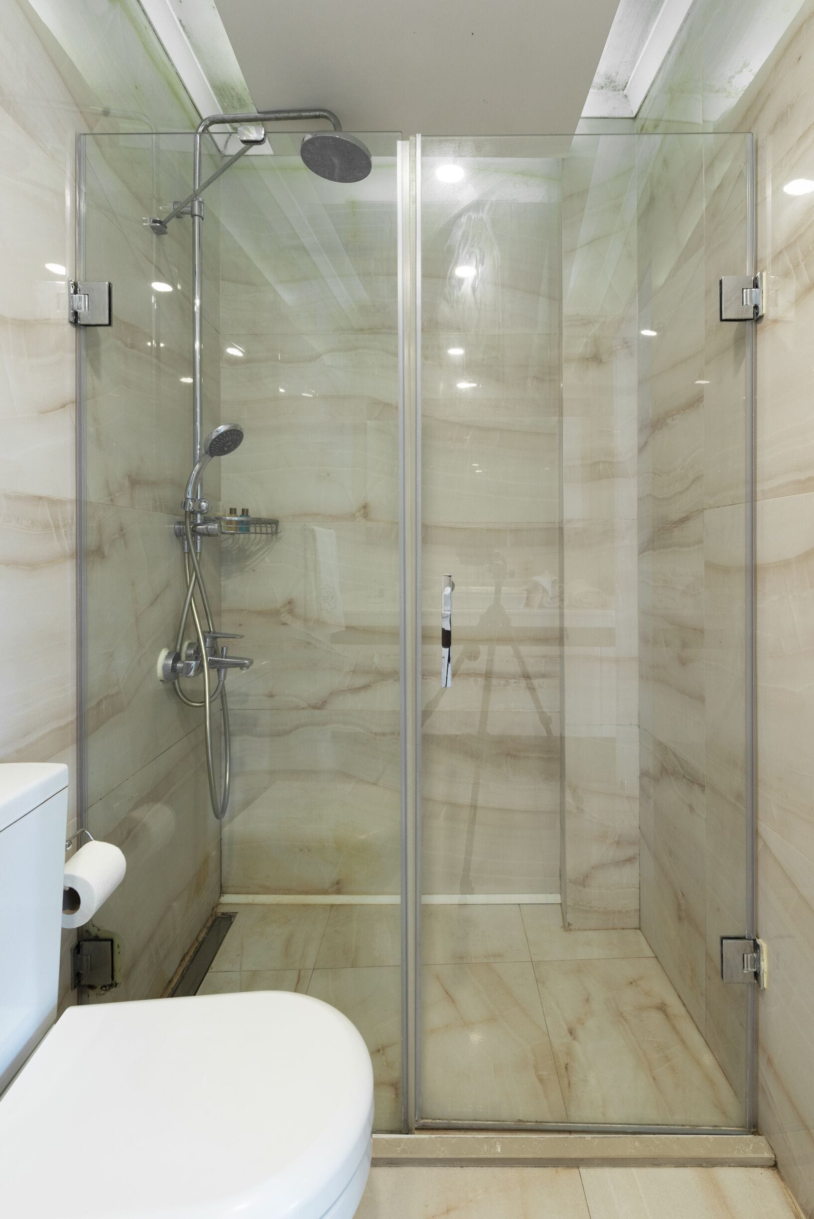 A glass-enclosed shower stall with a toilet to the left.