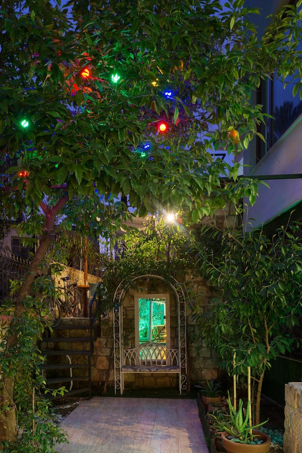 A stone staircase leading to a bench under a tree with colorful lights. - Delight Deluxe Aparts (Antalya)