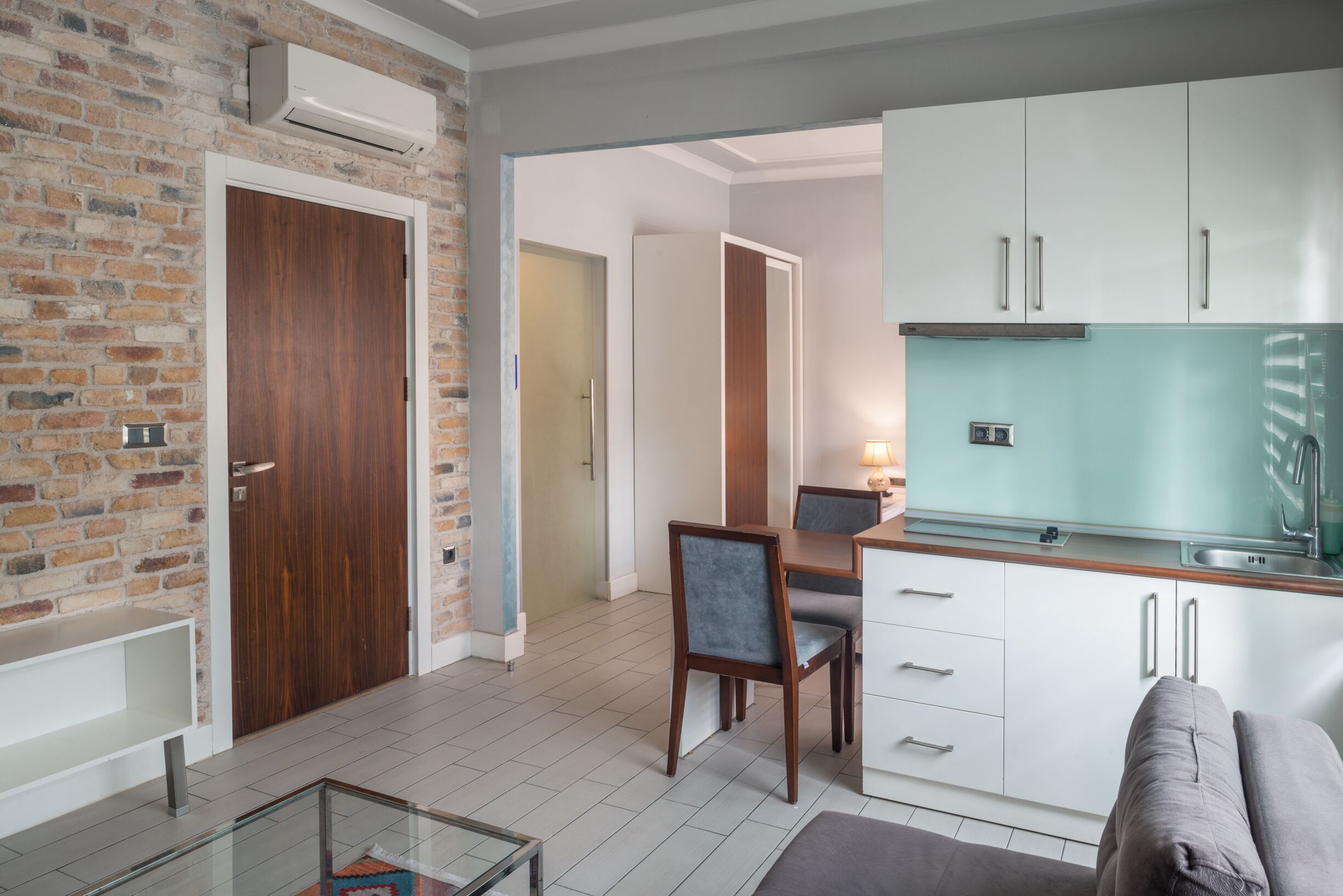 A modern kitchen with white cabinets, a built-in oven, and a glass backsplash.