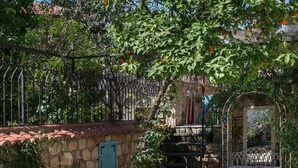 Un patio al aire libre con muro de piedra, una puerta metálica y una mesa con sillas.