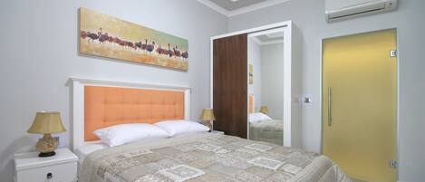 A bedroom with a large bed, a nightstand, a painting, and a door.